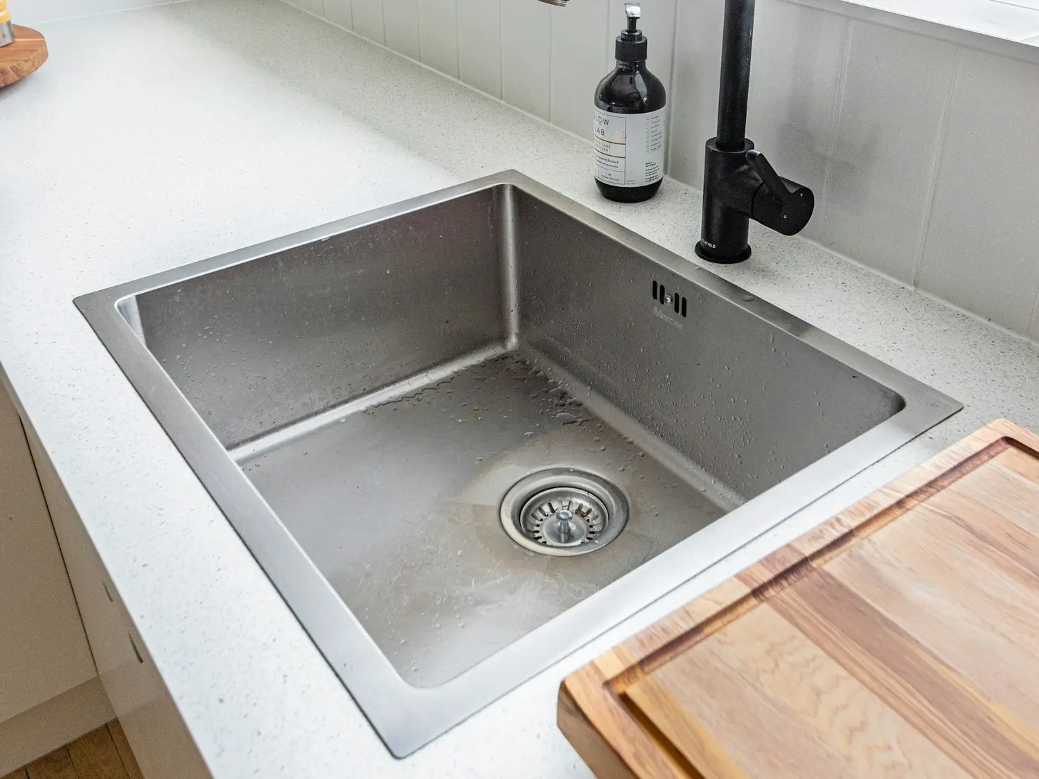 A stainless steel kitchen sink set into a light countertop